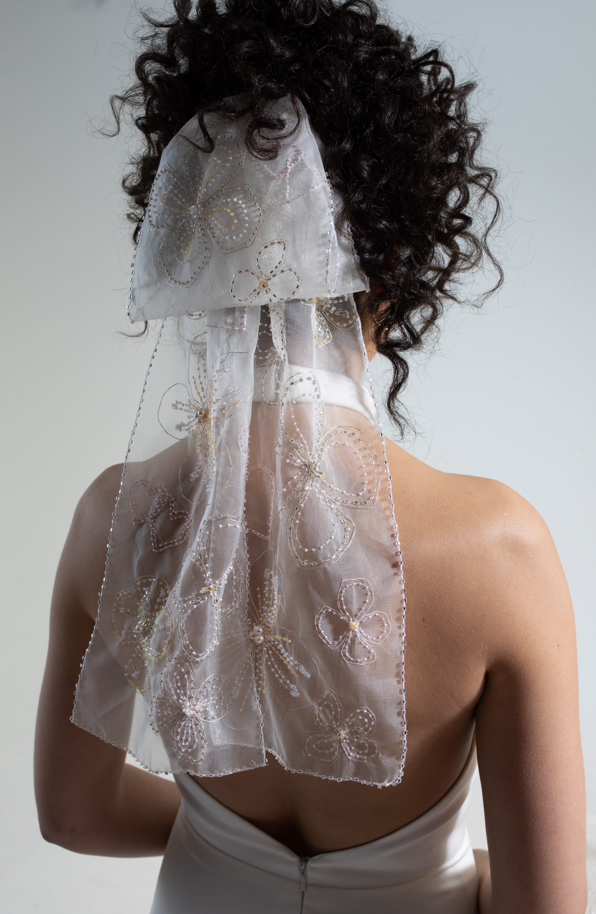 Hand embellished silk organza bow veil. A bridal bow hand-embroidered in a floral design as part of a collection of luxury decorative bridal accessories and bridal headwear.