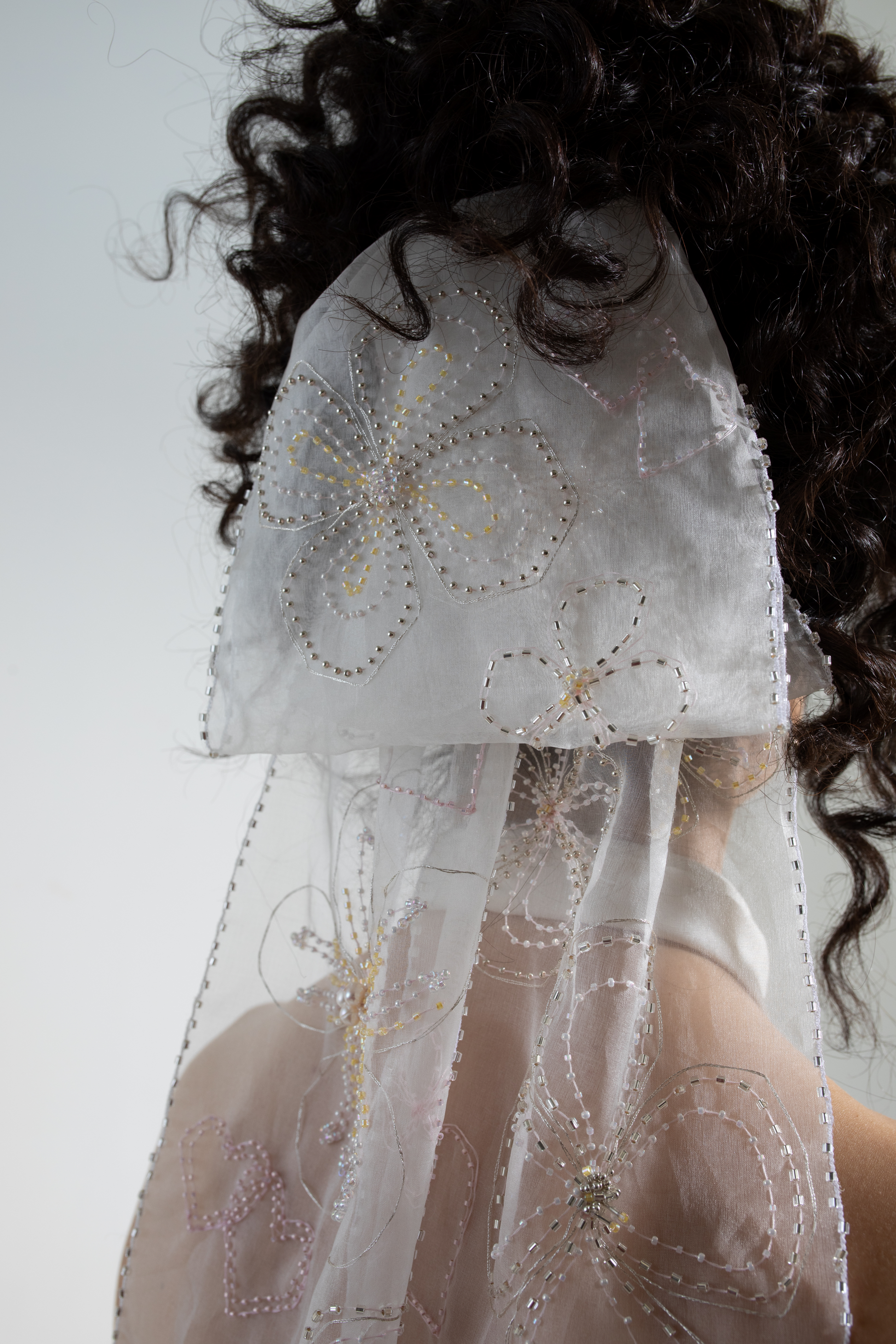 Hand embellished silk organza bow veil. A bridal bow hand-embroidered in a floral design as part of a collection of luxury decorative bridal accessories and bridal headwear.